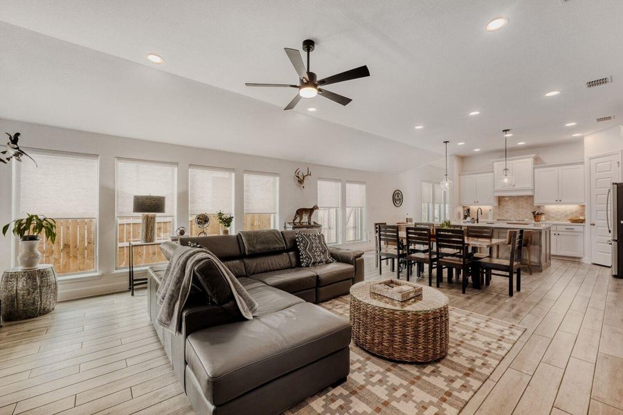 Living room with ceiling fan, light wood-style flooring, recessed lighting, and lofted ceiling