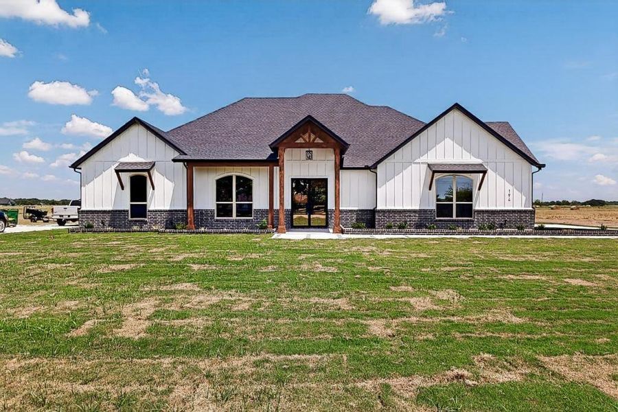 Modern farmhouse style home featuring board and batten siding, a front lawn, and roof with shingles