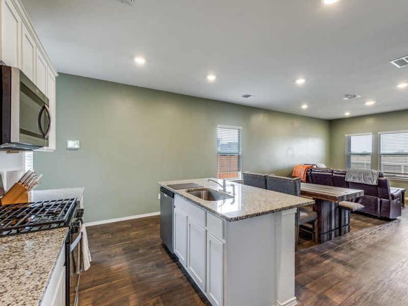 Kitchen featuring white cabinets, appliances with stainless steel finishes, light stone counters, recessed lighting, and open floor plan