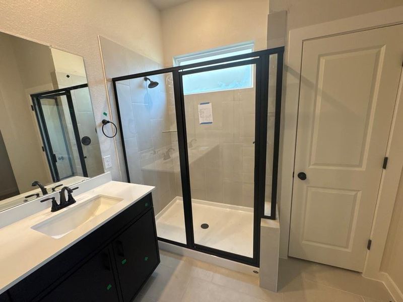 Full bathroom featuring a stall shower, vanity, and light tile patterned floors Full bathroom featuring a stall shower, vanity, and light tile patterned floors