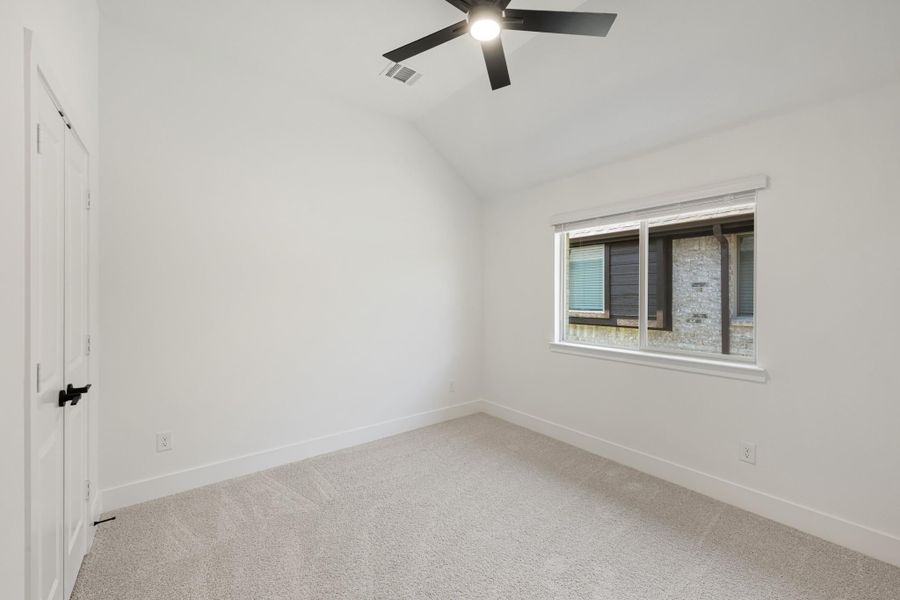 Empty bedroom with vaulted ceiling, ceiling fan, carpet flooring, and a single window