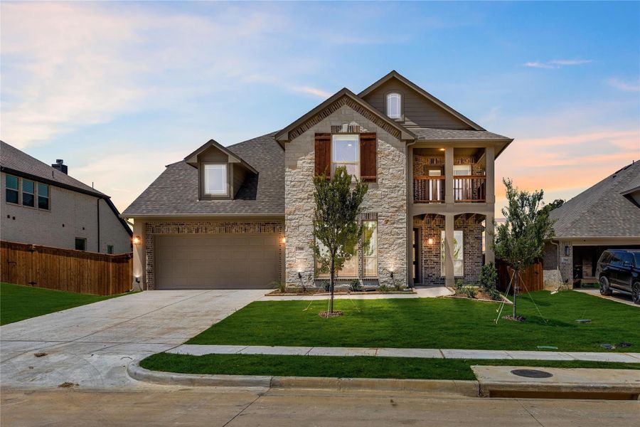 Two-story home with stone and brick exterior, two-car garage, upper balcony, and green front lawn at dusk Two-story home with stone and brick exterior, two-car garage, upper balcony, and green front lawn at dusk