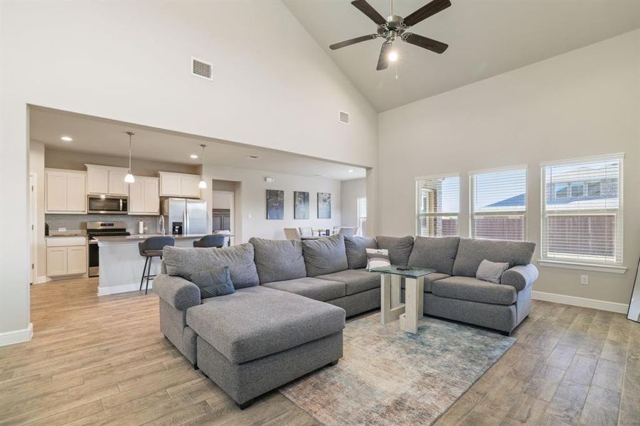 Living area with light wood-type flooring, ceiling fan, and lofted ceiling Living area with light wood-type flooring, ceiling fan, and lofted ceiling