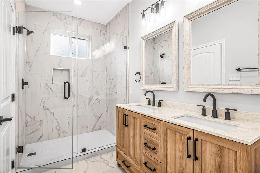 Double sinks in the primary bath with seamless glass shower enclosure.