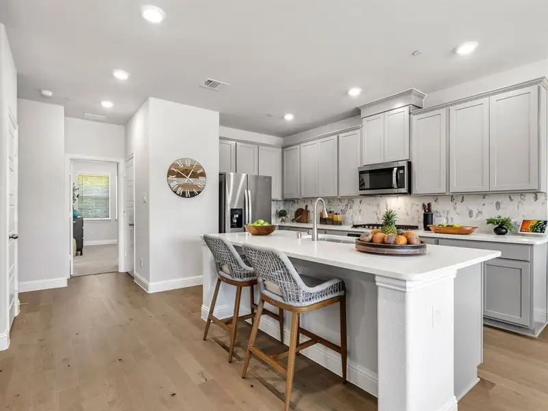 An abundance of crisp cabinetry paired with a designer tile backsplash offers exceptional kitchen organization and pantry space.