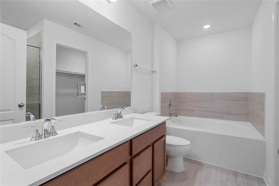 This primary bathroom is definitely move-in ready! Featuring stained cabinets with light countertops and dual vanities, oversized garden tub with custom tile, high ceilings, custom paint, sleek and dark modern finishes.