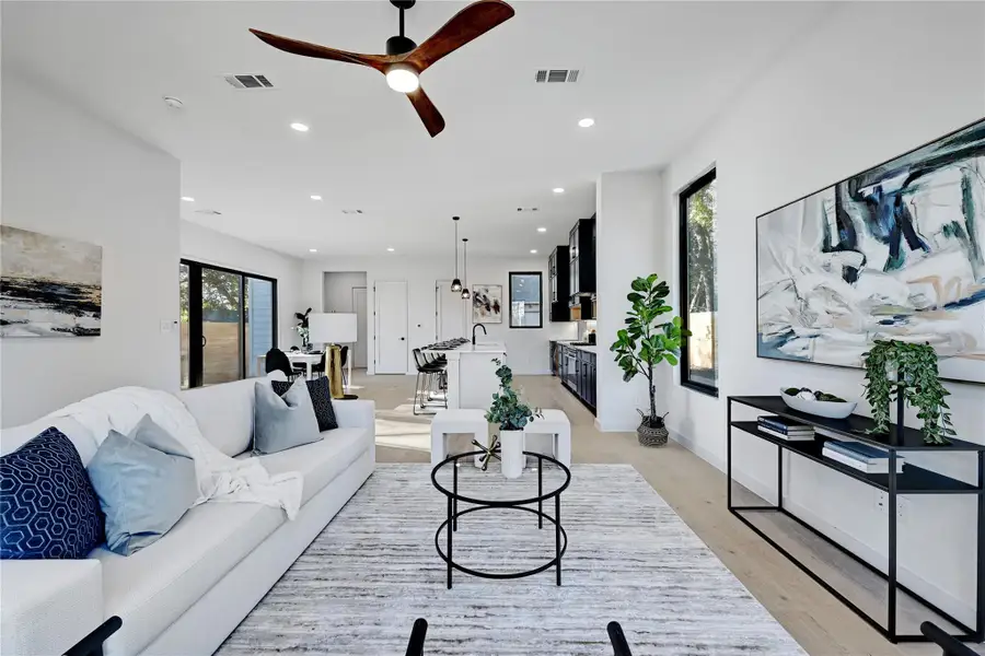 Living room with light wood-style floors, recessed lighting, visible vents, and a healthy amount of sunlight