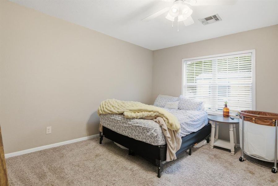 Carpeted room featuring a ceiling fan, a window with horizontal blinds, and neutral-toned walls