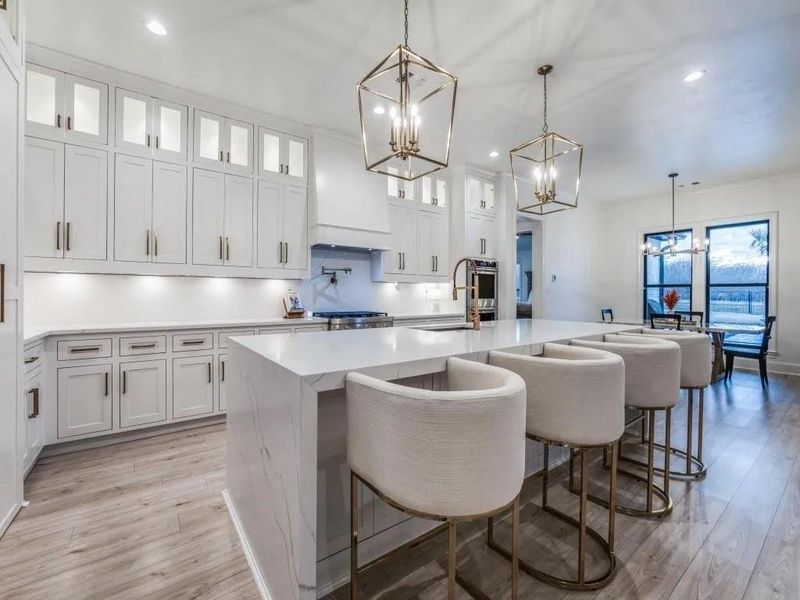 Kitchen with glass insert cabinets, a breakfast bar area, decorative light fixtures, white cabinets, and recessed lighting