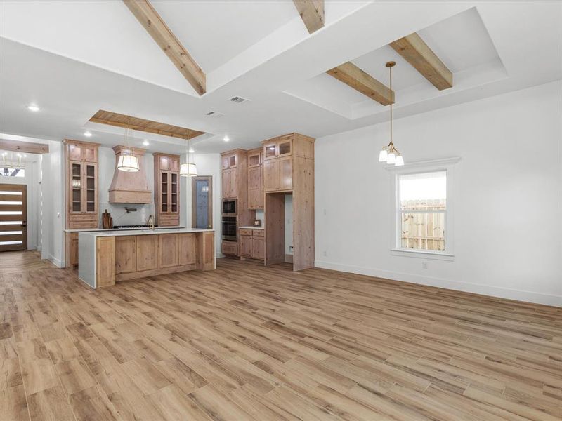 Kitchen with glass insert cabinets, open floor plan, beamed ceiling, and light wood-style floors