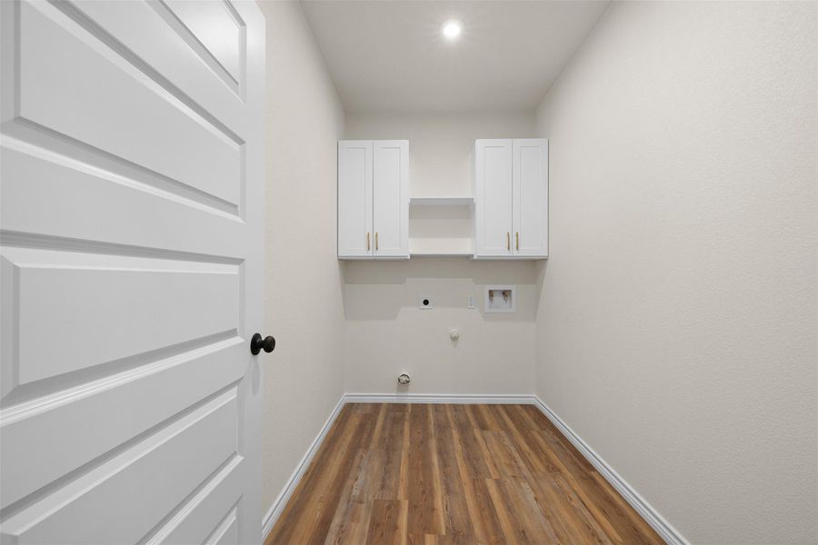 Laundry area featuring dark wood-style floors, hookup for a gas dryer, cabinet space, electric dryer hookup, and washer hookup Laundry area featuring dark wood-style floors, hookup for a gas dryer, cabinet space, electric dryer hookup, and washer hookup