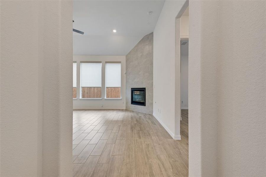 Unfurnished living room featuring light wood-style floors, a tile fireplace, lofted ceiling, and recessed lighting Unfurnished living room featuring light wood-style floors, a tile fireplace, lofted ceiling, and recessed lighting