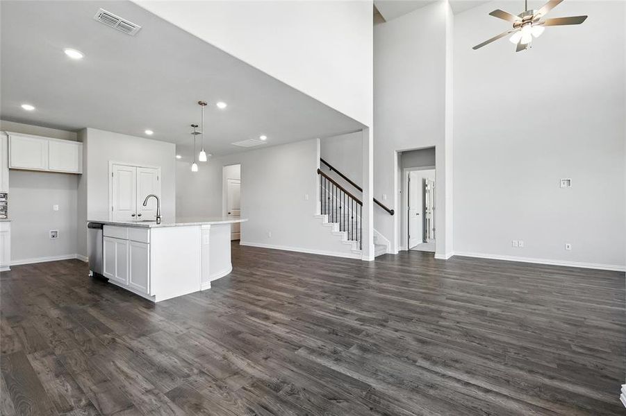 Kitchen with white cabinetry, a ceiling fan, an island with sink, open floor plan, and a high ceiling