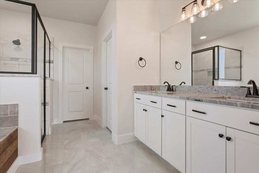 A well-appointed primary bathroom showcases dual vanities with elegant granite counters and a spacious walk-in shower.