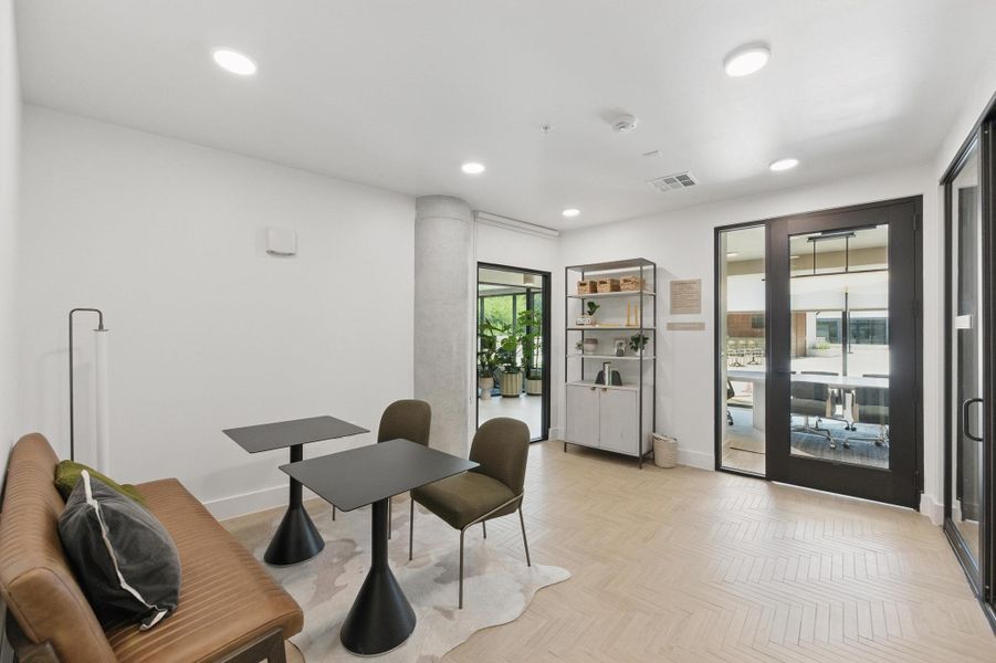 Herringbone-patterned hardwood floors grace this naturally illuminated community room, perfect for collaborative work or quiet reflection.