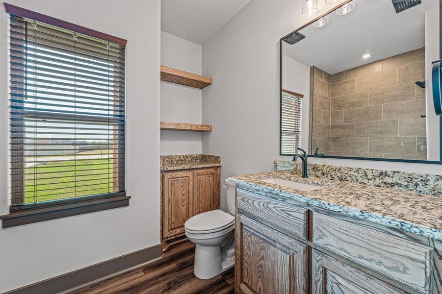 Full bathroom with vanity, dark wood-style floors, and tiled shower