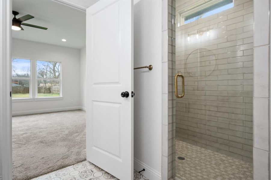 Bathroom featuring a shower stall, baseboards, and a ceiling fan