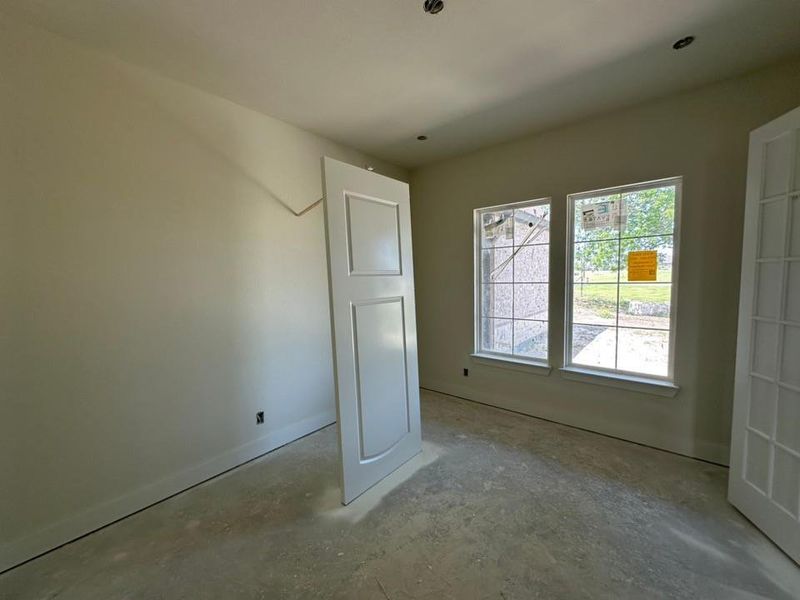 Two large windows with white trim, two unfinished doors, and recessed lighting
