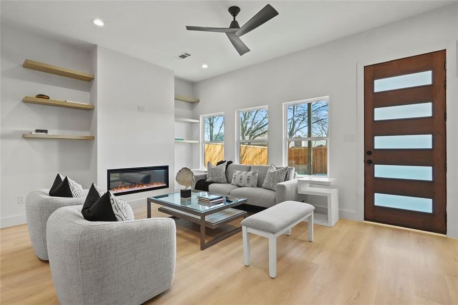 Living room featuring built in features, ceiling fan, light wood-style flooring, a glass covered fireplace, and recessed lighting