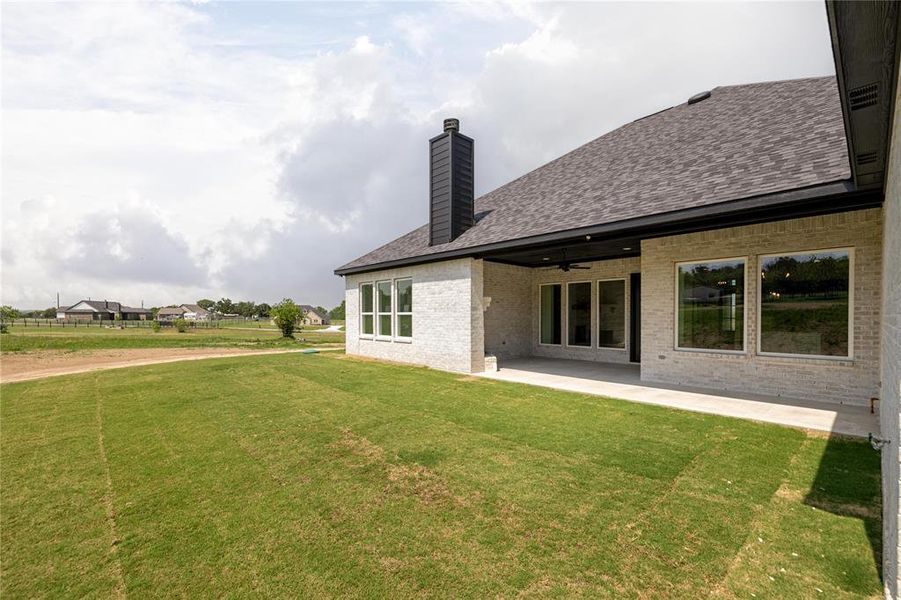 Rear view of house with a lawn and a patio