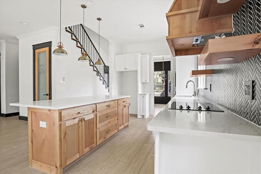 Kitchen featuring under cabinet range hood, ornamental molding, open shelves, light wood finished floors, and light brown cabinets