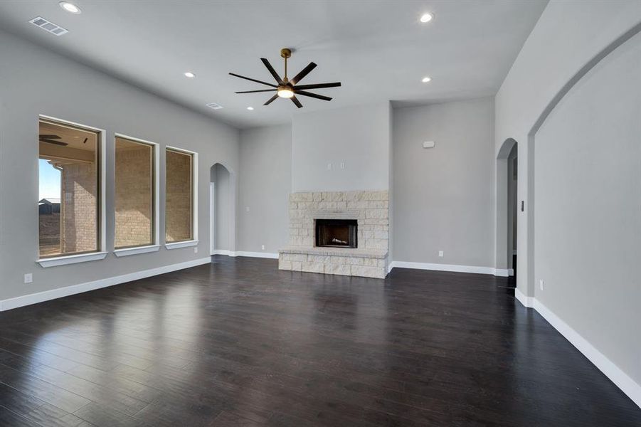 Unfurnished living room with a fireplace, dark hardwood / wood-style flooring, and ceiling fan