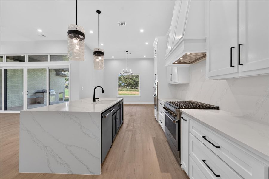 High ceilings and clean lines define this modern kitchen with stone countertops and wood flooring.