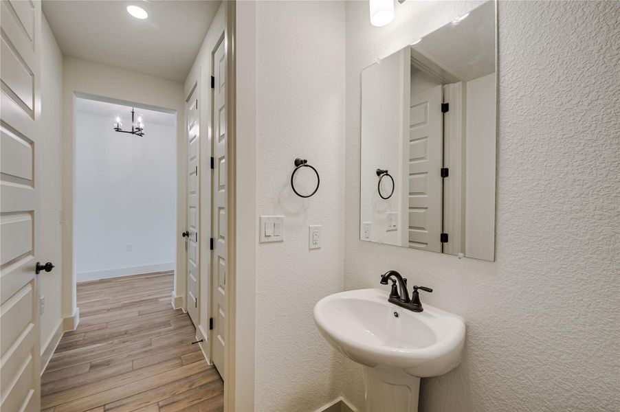 Bathroom featuring light wood finished floors, a textured wall, and recessed lighting