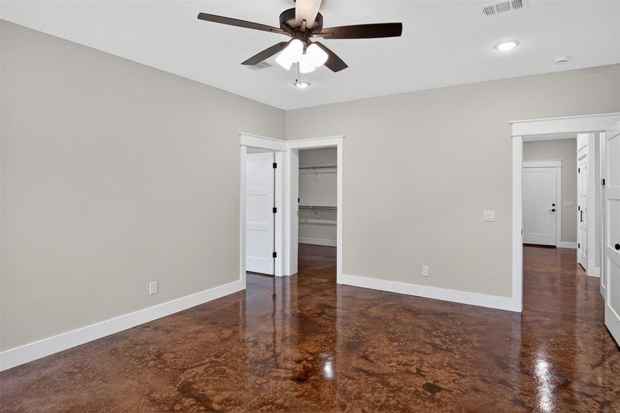 Primary Spacious interior featuring a contemporary ceiling fan, recessed lighting, stained concrete flooring, and crisp white trimwork Primary Spacious interior featuring a contemporary ceiling fan, recessed lighting, stained concrete flooring, and crisp white trimwork
