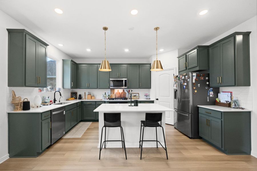 Spacious kitchen featuring dark green cabinetry, white countertops, a white subway tile backsplash, and light wood-finish flooring