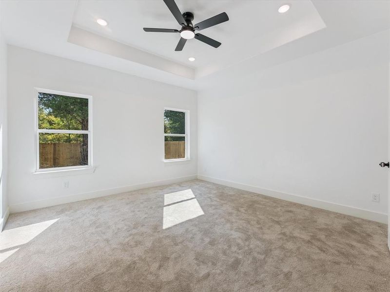 Carpeted spare room with a raised ceiling, recessed lighting, and ceiling fan