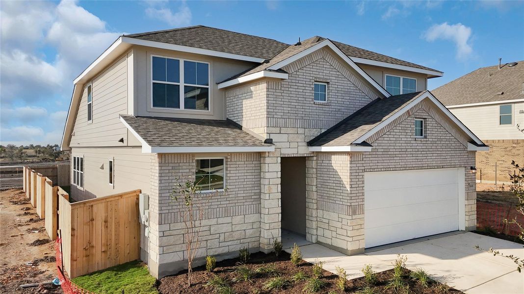 View of front of home featuring a shingled roof, concrete driveway, and brick siding