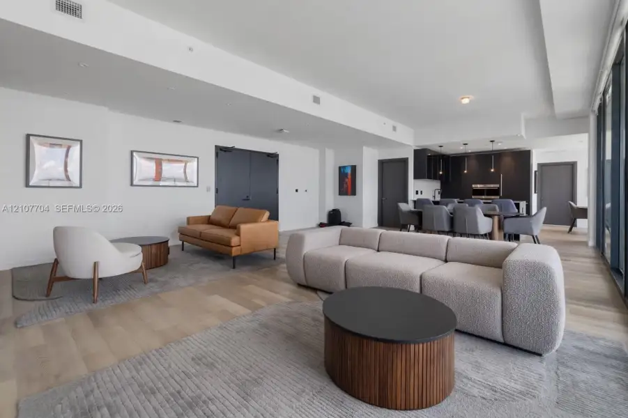 Open-concept floor plan featuring wood-finish flooring, high ceilings, recessed lighting, and kitchen cabinetry with integrated appliances