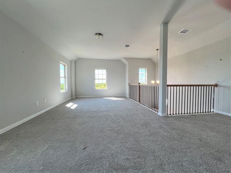 Carpeted spare room featuring vaulted ceiling and a chandelier