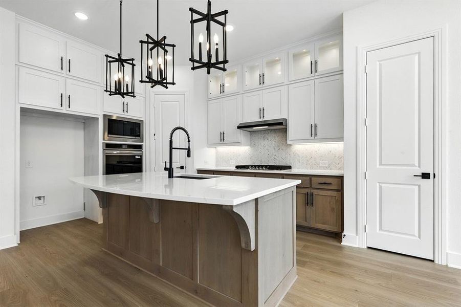 Kitchen with a center island with sink, decorative backsplash, a kitchen breakfast bar, pendant lighting, and white cabinets Kitchen with a center island with sink, decorative backsplash, a kitchen breakfast bar, pendant lighting, and white cabinets