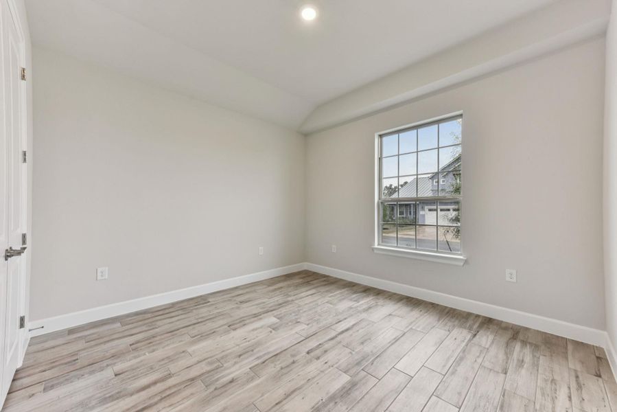 Empty room featuring light wood-style flooring, vaulted ceiling, and recessed lighting