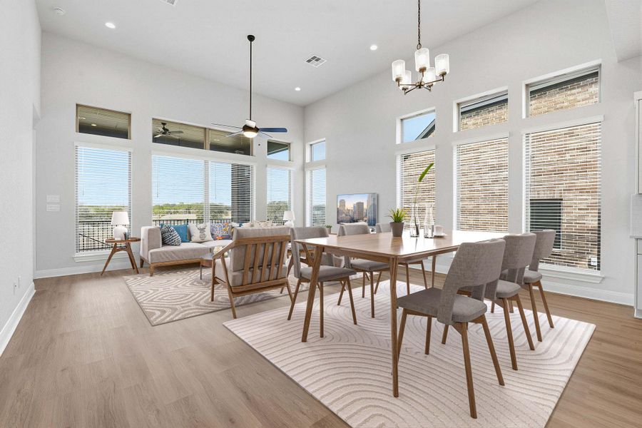 Dining space with suspended lighting, a high ceiling, light wood-style floors, and ceiling fan