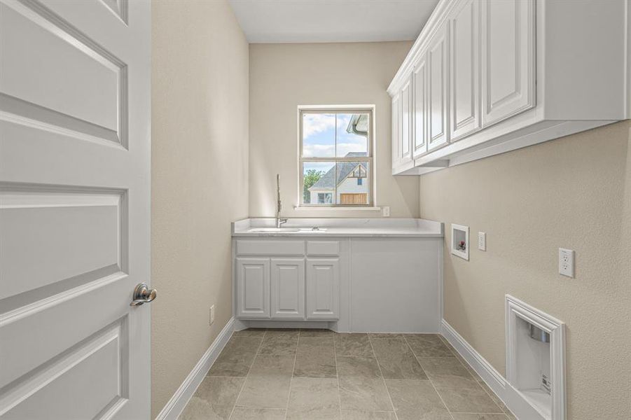 Clothes washing area featuring sink, light tile patterned floors, cabinets, and hookup for a washing machine