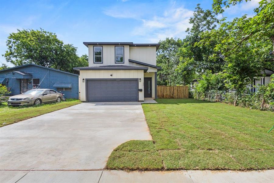 Contemporary two-story exterior featuring a light-colored facade with dark trim, a prominent two-car garage, and a concrete driveway Contemporary two-story exterior featuring a light-colored facade with dark trim, a prominent two-car garage, and a concrete driveway