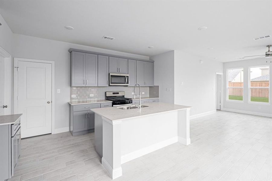 Kitchen featuring a kitchen island with sink, a sink, visible vents, appliances with stainless steel finishes, and gray cabinets