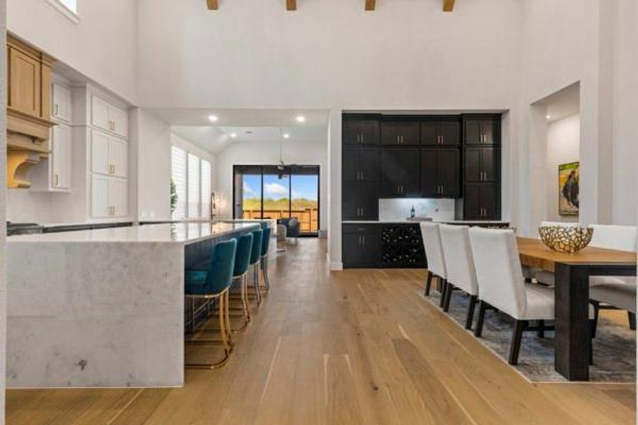 Kitchen with a kitchen bar, healthy amount of natural light, a high ceiling, dark cabinetry, and light wood-style floors
