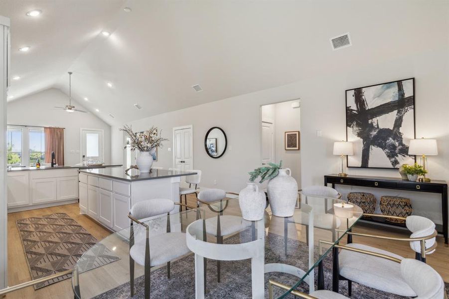 Dining room featuring light wood-type flooring, sink, ceiling fan, and high vaulted ceiling