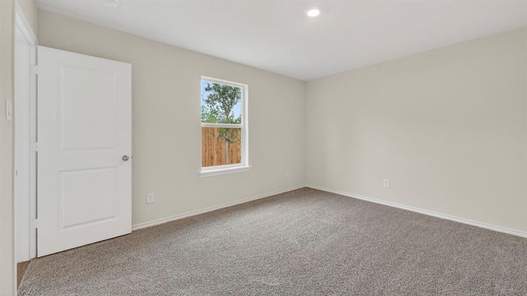 Spacious room featuring neutral paint, gray carpet flooring, a white window frame, and a modern white two-panel door