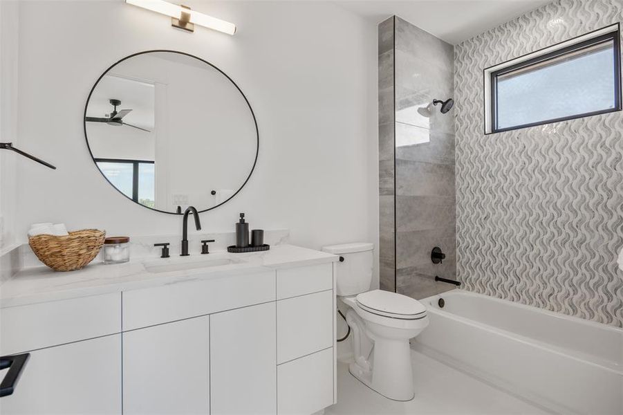 A refined bathroom featuring a contemporary vanity with a marble countertop, sleek fixtures, and an elegant tiled shower and tub.