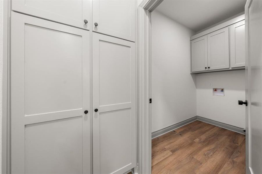 Washroom featuring dark wood-style floors, cabinet space, and washer hookup