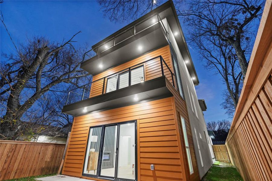 Back of house at twilight with a balcony and a patio Back of house at twilight with a balcony and a patio