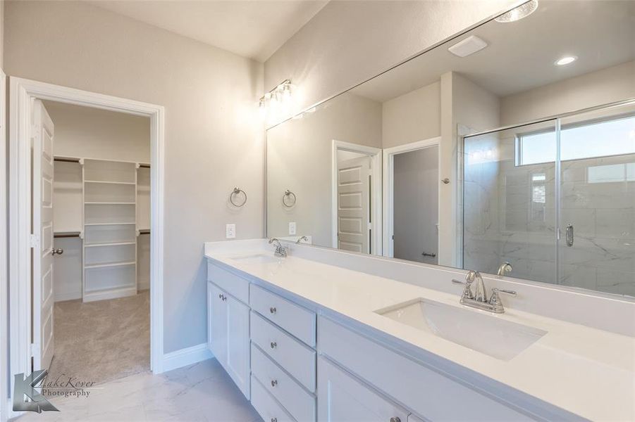 Full bathroom featuring double vanity, light tile patterned flooring, and a stall shower