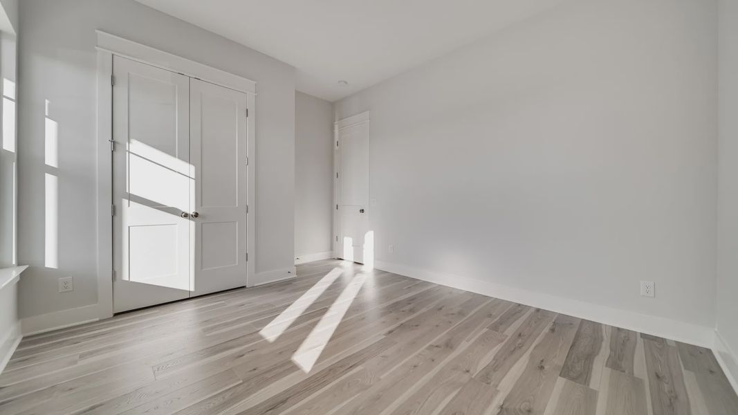 Secondary bedroom with hard-surface flooring and large windows with closet