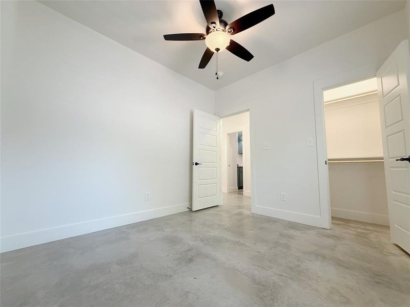 Unfurnished bedroom featuring concrete flooring, a closet, baseboards, and ceiling fan Unfurnished bedroom featuring concrete flooring, a closet, baseboards, and ceiling fan