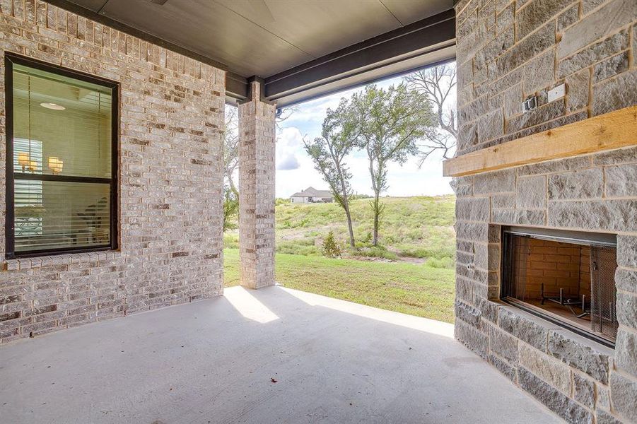 View of covered patio with ceiling fan and an outdoor stone fireplace View of covered patio with ceiling fan and an outdoor stone fireplace